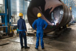 Two experienced workers supervising the manufacture of a metalli